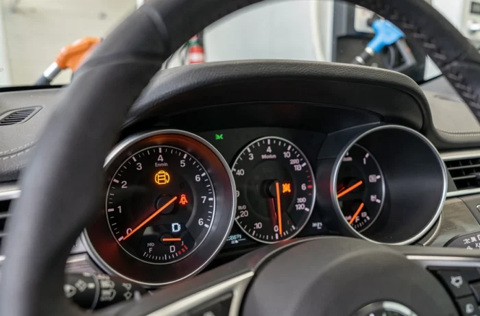 Gros plan sur le voyant moteur orange allumé sur le tableau de bord d'une voiture moderne à la station-service